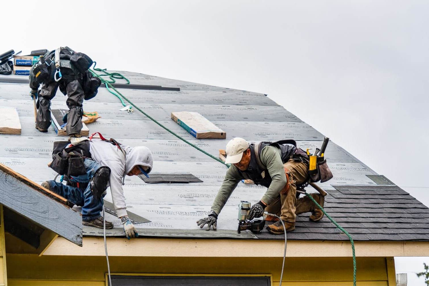 Professional roofing contractors installing roofing materials with safety equipment
